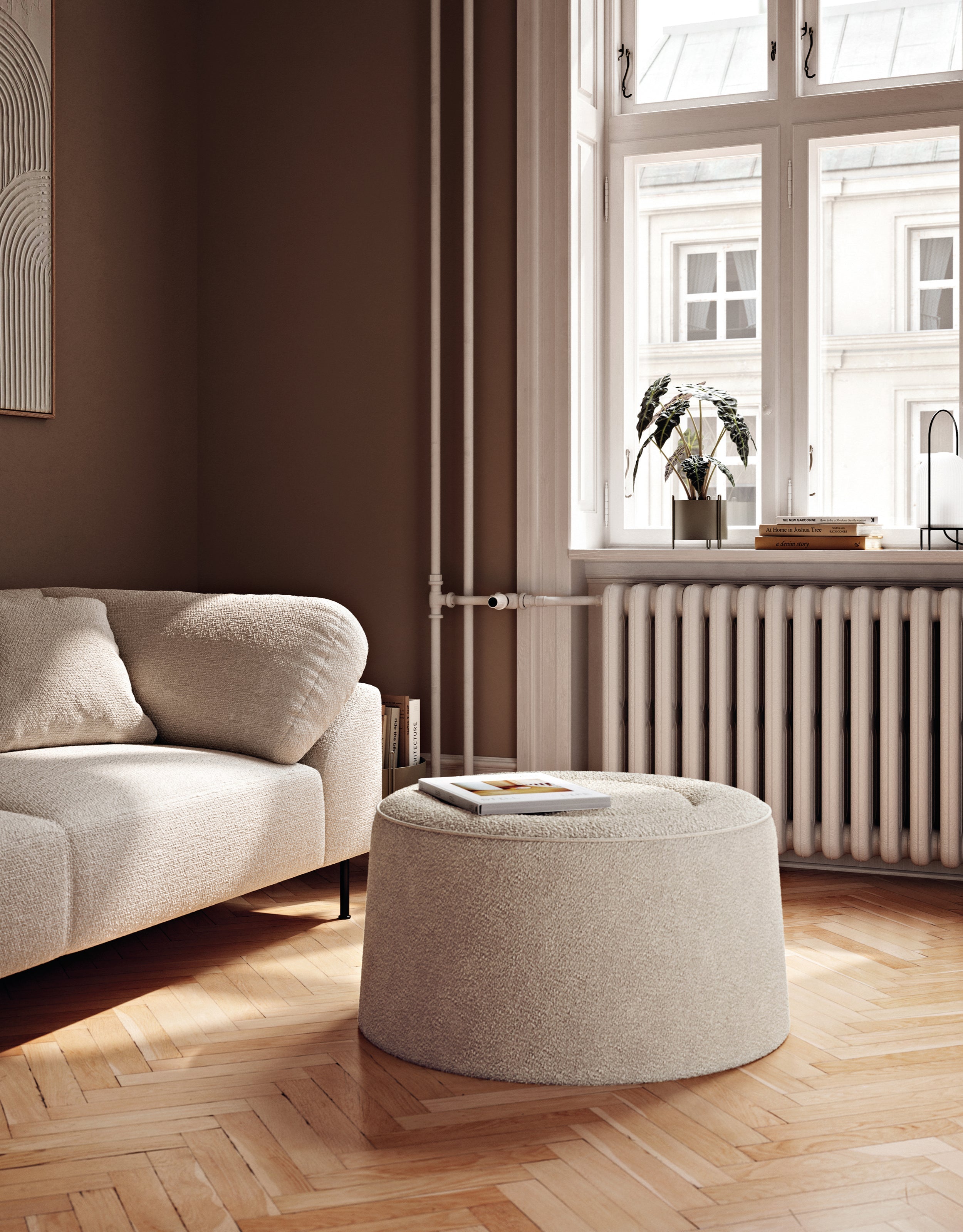 Round beige pouf placed in front of sofa in a Scandinavian living room.