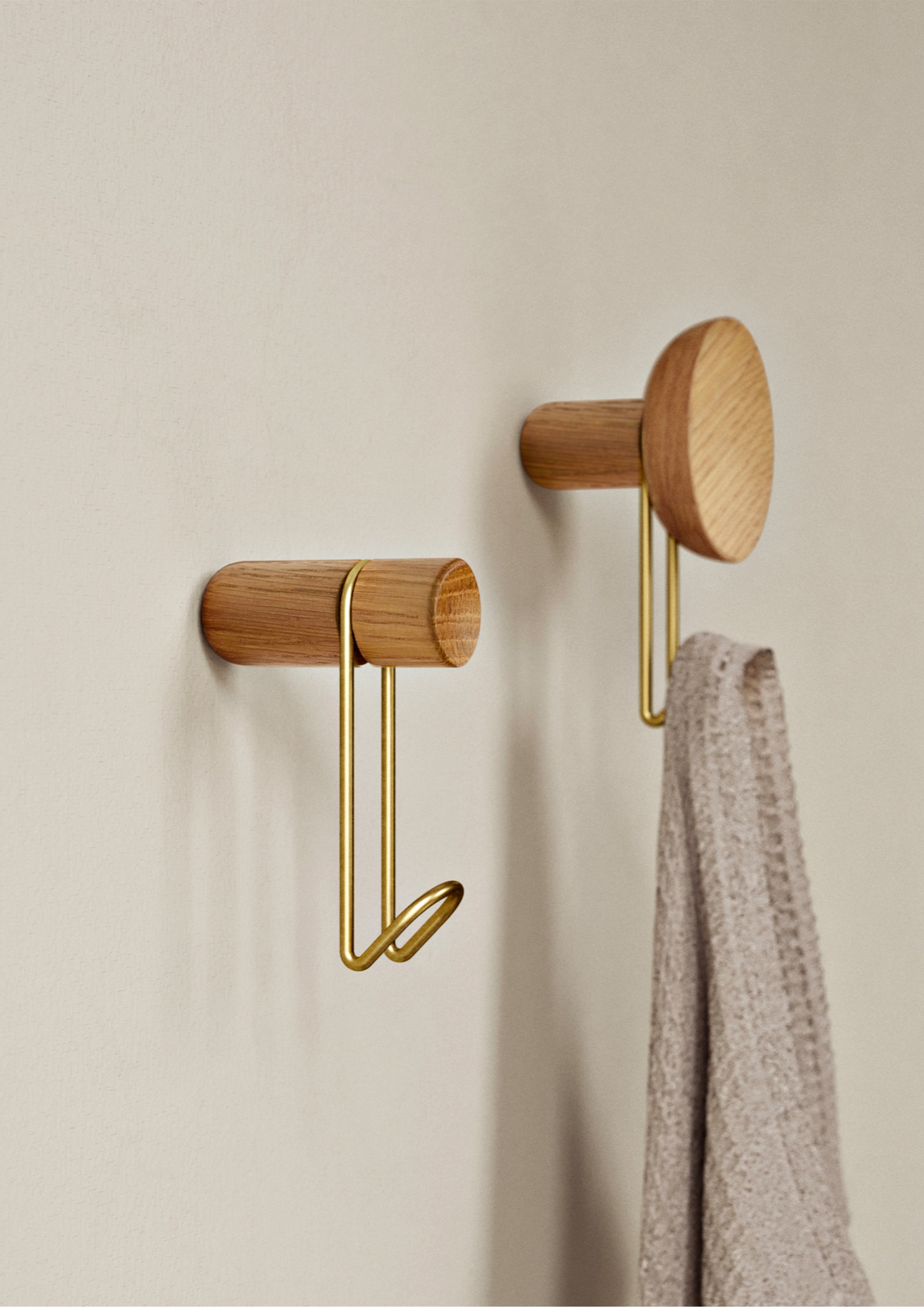 Two hooks in white pigmented oak with satin brass plated metal hook.