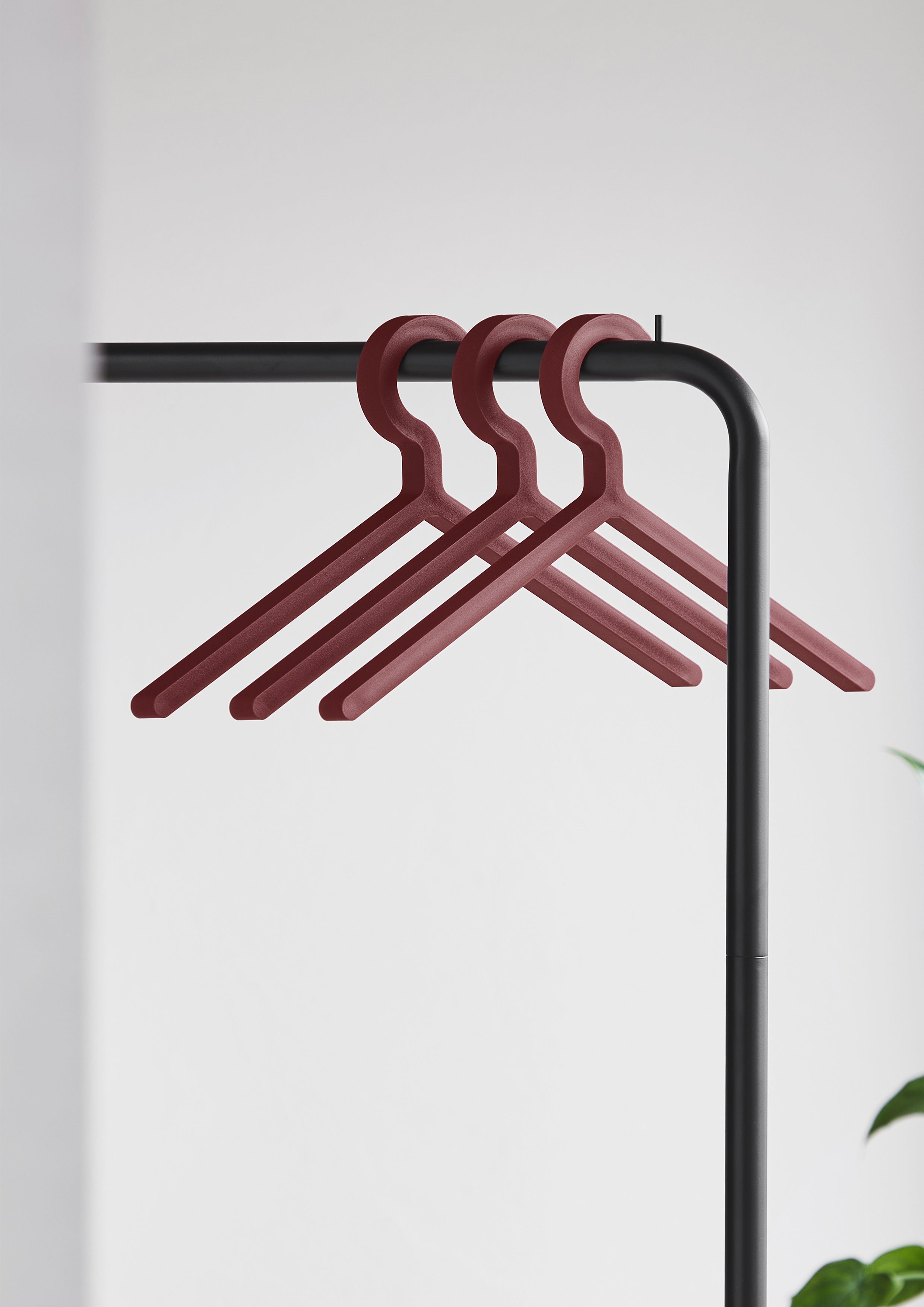 Three hangers in deep red on a black clothes rack.