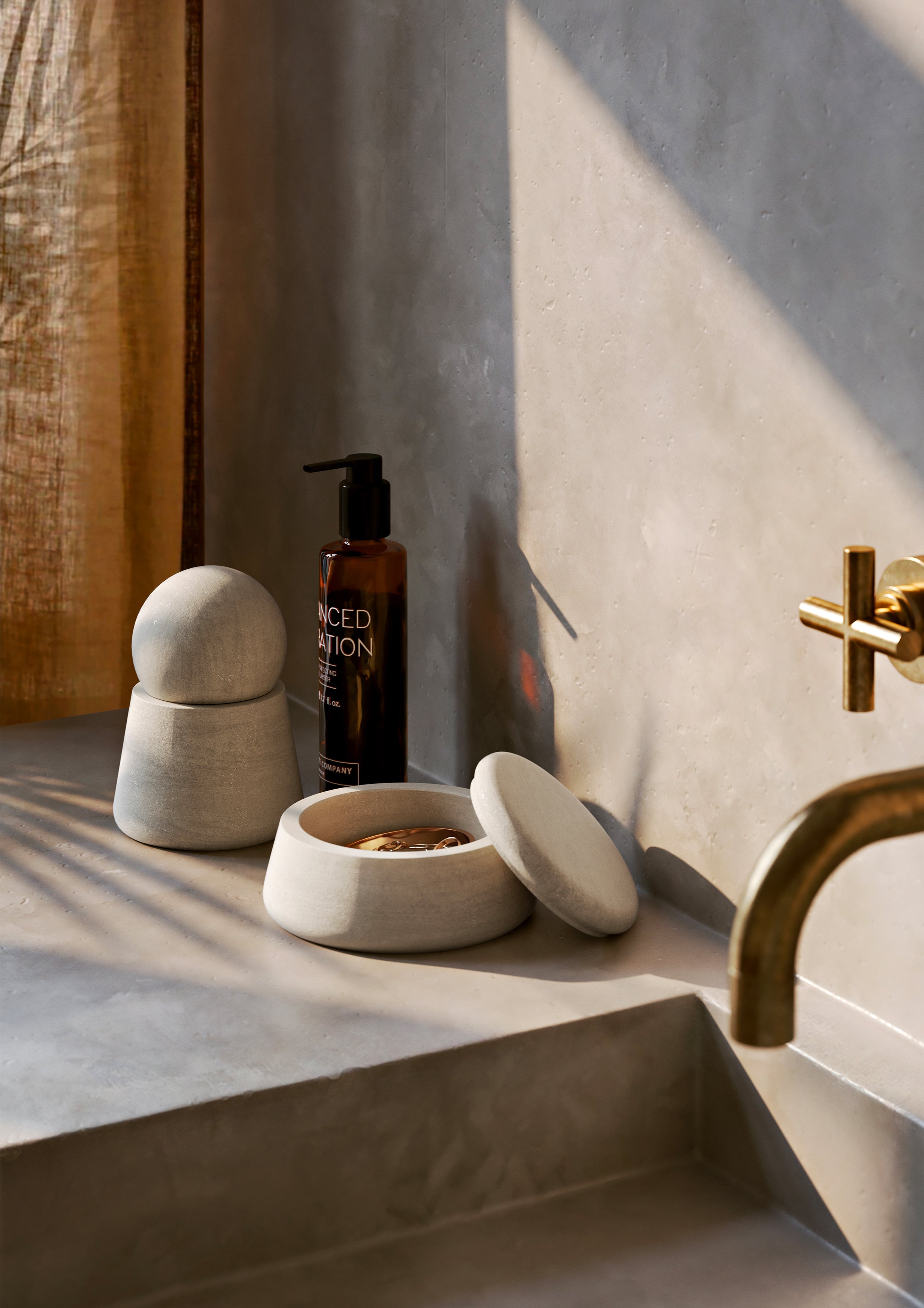 A pair of round jars in natural sandstone placed on a countertop next to the sink.